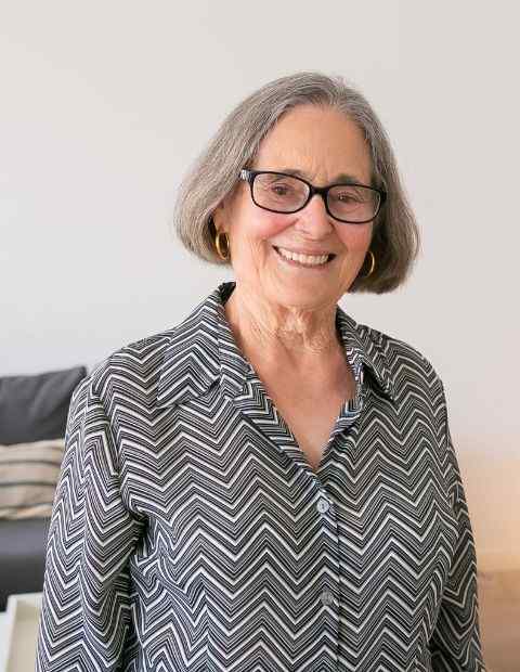 Martha Williams portrait picture. She is the founder of the blog page The Sewing Mama. She has grayish hair, glasses and is approximately 60 years old. She has a striped blouse with black glasses and golden earrings.